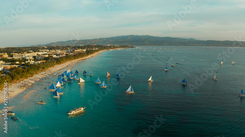 Aerial view of sailing boats on the sandy beach of Boracay Island at sunset time. Tropical white beach with sailing boat. Summer and travel vacation concept.