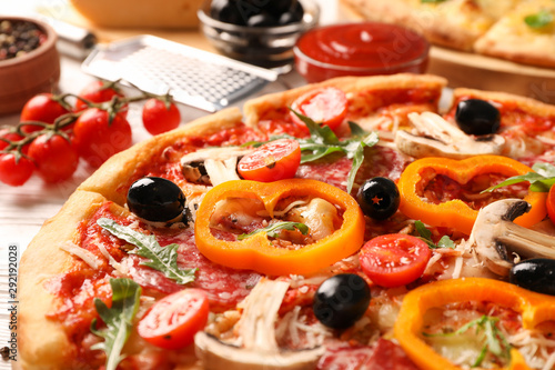 Delicious pizza and ingredients on white wooden background, close up