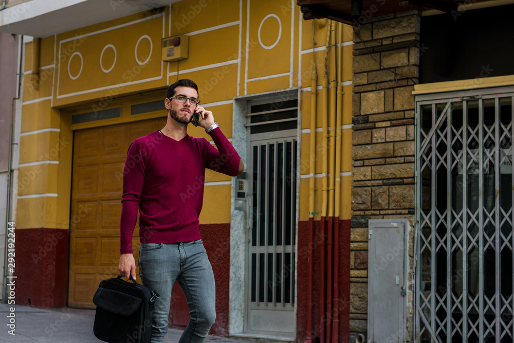 Young businessman is walking on the street while he is talking with his phone Young businessman is walking on the street while he is talking with his phone