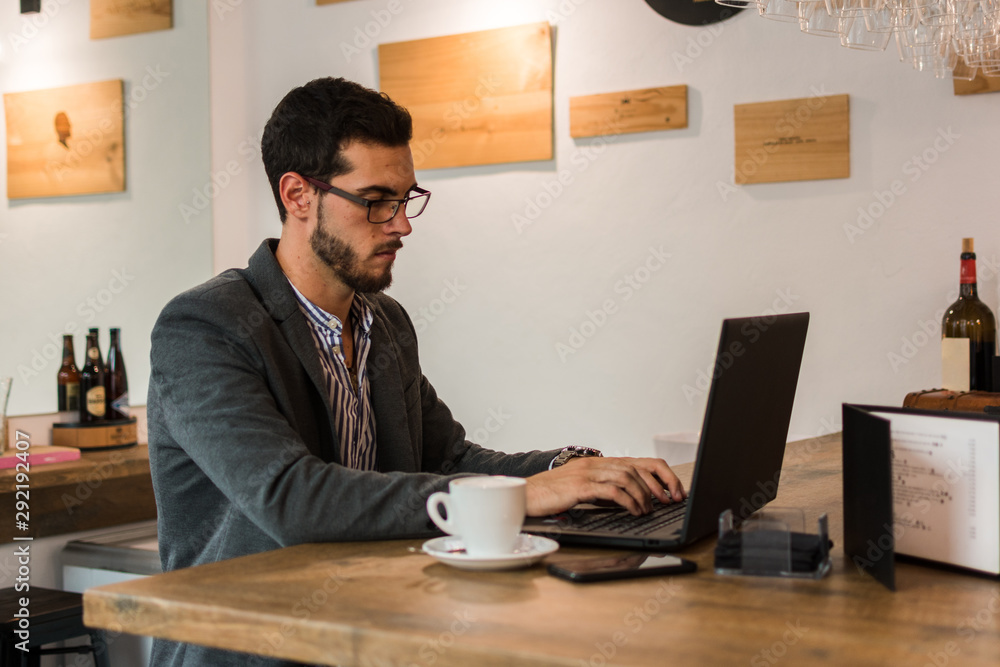 Young businessman in a pub working with his laptop Young businessman in a pub working with his laptop