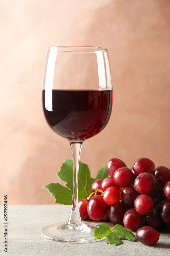 Grape and glass with wine on grey background, space for text Grape and glass with wine on grey background, space for text