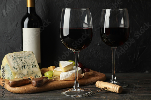 Cheese, grape, bottle and glasses with wine on wooden background. Wine tasting