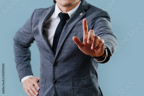 Businessman in suit making objection gesture , holding index finger up over blue