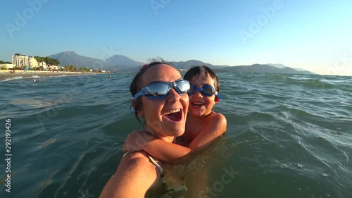 Fethiye, Turkey - 19th of September 2019: 4K Smiling mother and her son turn around in the sea making selfie