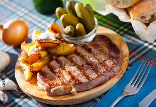 Appetizing beef entrecote with boiled potatoes and pickled cucumbers