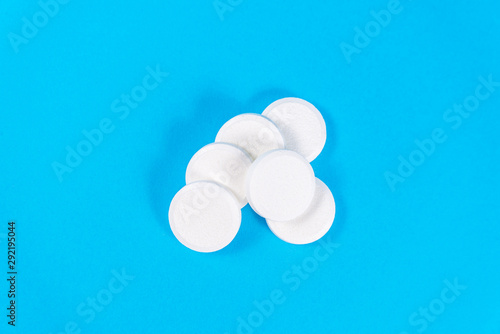 A stack of vitamin and mineral Supplement effervescent tablets isolated on a blue background. Lots of big soluble round tablets for sore throats, colds, fever and headaches. copy space
