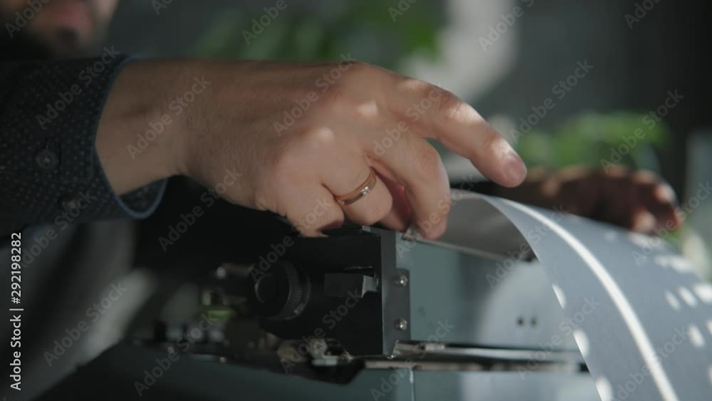 Men's hands with a wedding ring load paper in the tray of a typewriter. The beginning of creativity. Close-up, typewriter, vintage atmosphere. Taken from the side. Men's hands with a wedding ring load paper in the tray of a typewriter. The beginning of creativity. Close-up, typewriter, vintage atmosphere. Taken from the side.