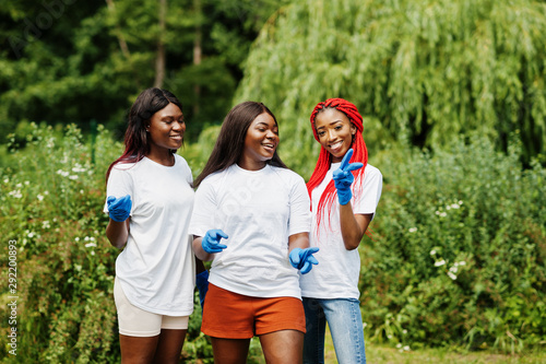 Three african volunteer womans in park. Africa volunteering, charity, people and ecology concept.