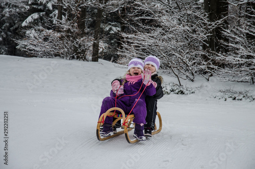 happy smiling children having fun with sledge in winter forest