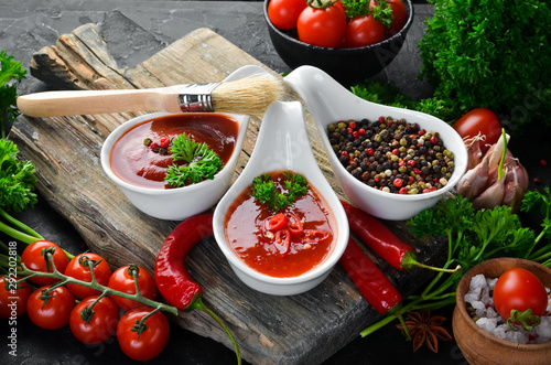 A set of tomato sauces on a black stone background. Ketchup, barbecue sauce, tomato sauce. Top view. Free space for your text.