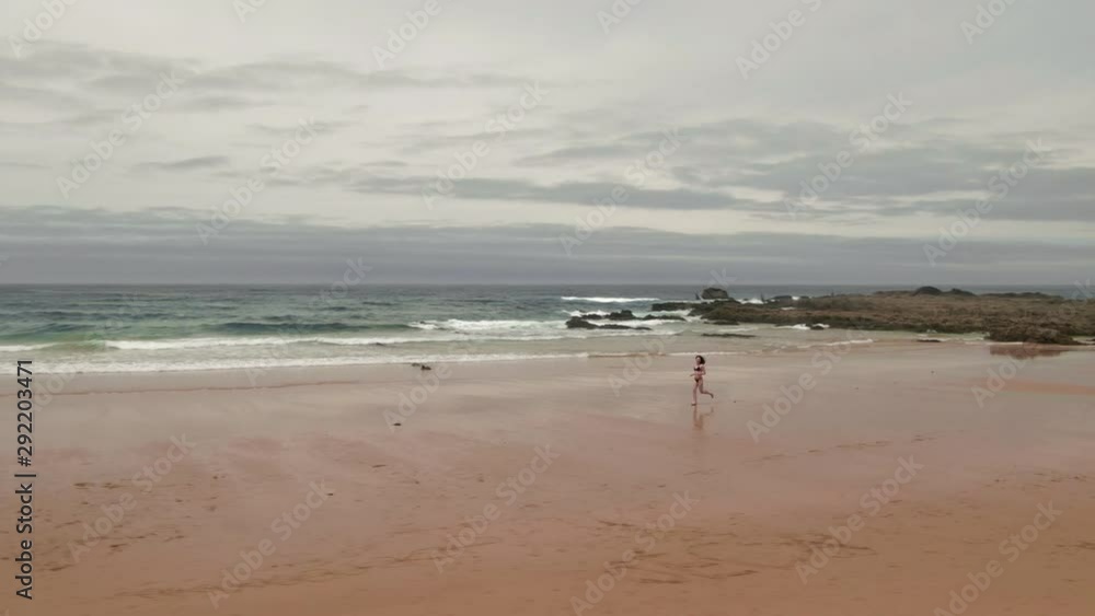 Aerial drone view young woman running on a beach on Praia de Amoreira, Portugal Aerial drone view young woman running on a beach on Praia de Amoreira, Portugal
