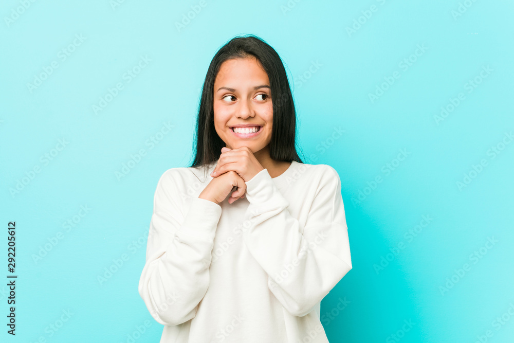 Young pretty hispanic woman keeps hands under chin, is looking happily aside. Young pretty hispanic woman keeps hands under chin, is looking happily aside.
