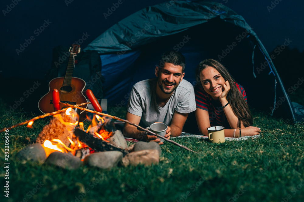 happy couple on night camping by the camping fire