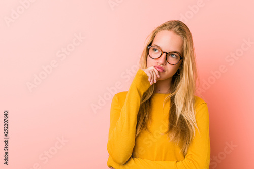 Adorable teenager woman looking sideways with doubtful and skeptical expression.