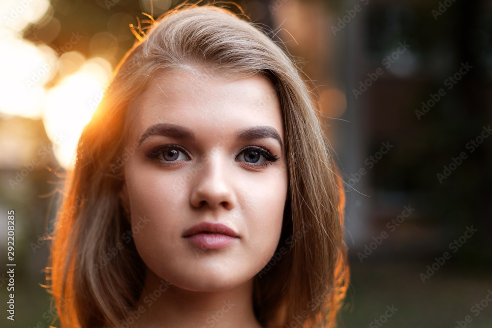 Closeup portrait of a young attractive girl in backlight against blurred background. Shallow focus. Copyspace. Closeup portrait of a young attractive girl in backlight against blurred background. Shallow focus. Copyspace.