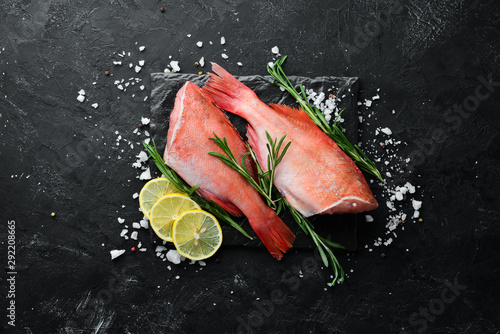Fish raw snapper with lemon and rosemary. On a black background. Top view. Free space for your text.
