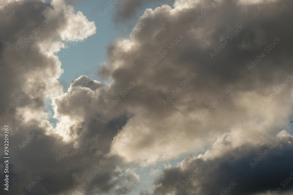 The sun and clouds on the blue sky. Cloudy weather with cumulus, dark clouds. Autumn day. A strong wind blows, the pressure is low, the threshold of rain. The sun and clouds on the blue sky. Cloudy weather with cumulus, dark clouds. Autumn day. A strong wind blows, the pressure is low, the threshold of rain.