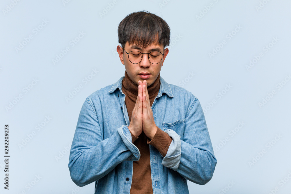 Young chinese man praying very happy and confident Young chinese man praying very happy and confident