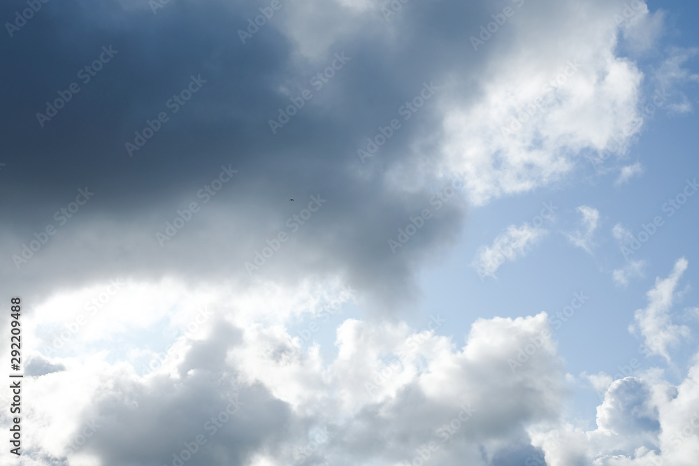 The sun and clouds on the blue sky. Cloudy weather with cumulus, dark clouds. Autumn day. A strong wind blows, the pressure is low, the threshold of rain.