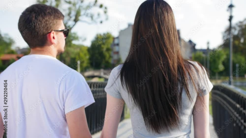Happy young couple walking in the park going on the bridge. Couple Trust, Love and Happiness concept. Close up shot. Happy young couple walking in the park going on the bridge. Couple Trust, Love and Happiness concept. Close up shot.