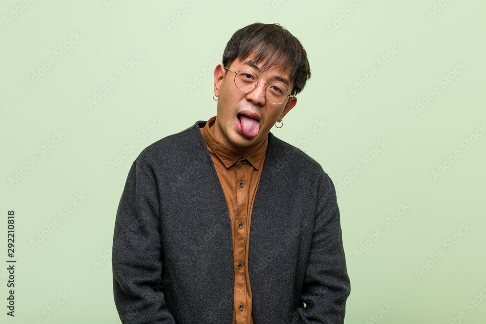 Young chinese man against a green wall Young chinese man against a green wall