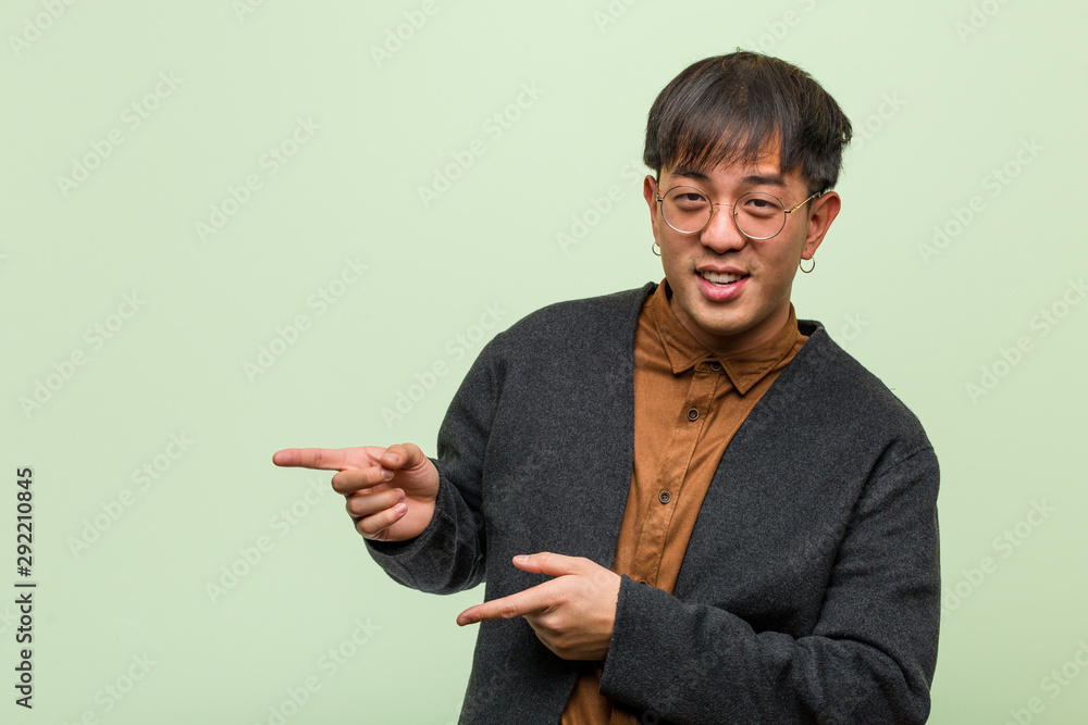 Young chinese man wearing a cool clothes style against a green background