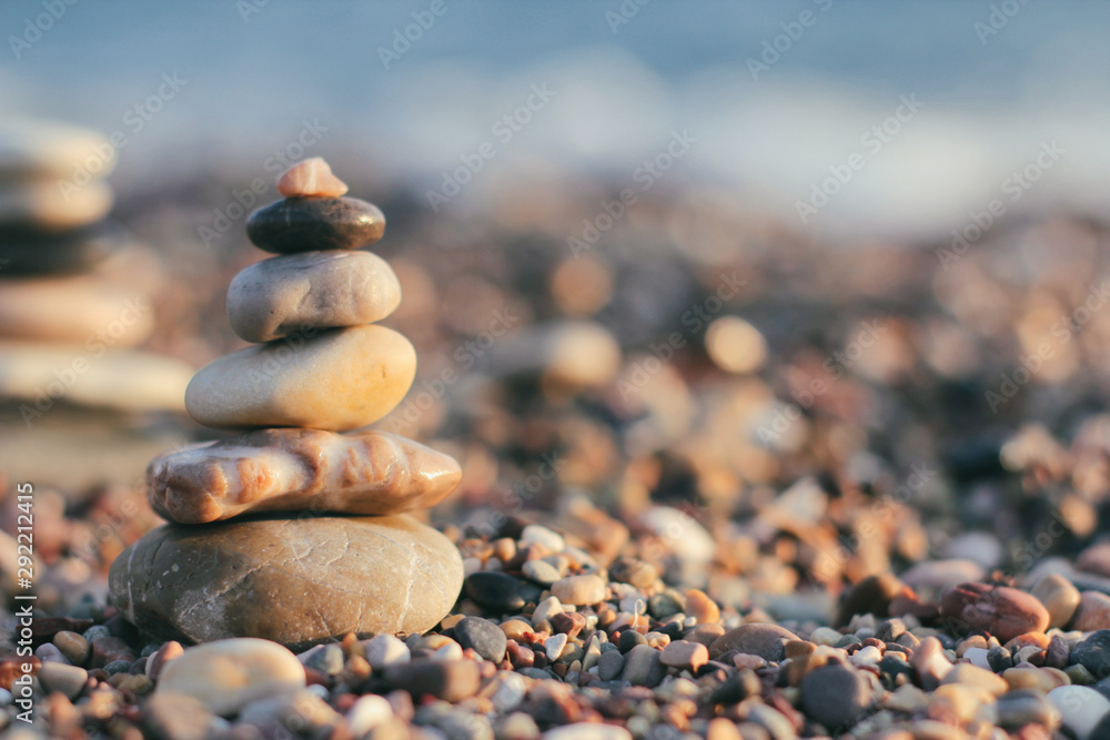 Zen pyramid of spa stones on the blurred sea background. Sand on a beach. Sea shores. Place for text. Sea view. 