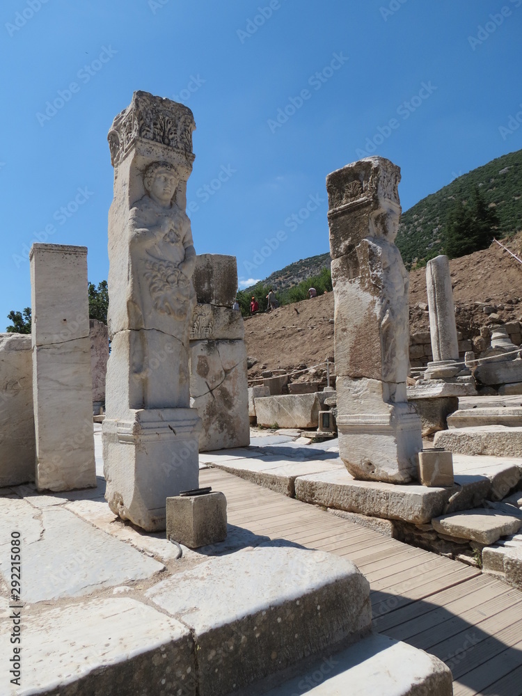 Part of the ancient city of Ephesus in Turkey: columns with images of the people of the ancient city of Ephesus against the blue sky