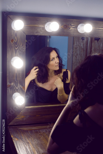 woman in a black jacket looks at herself in the mirror