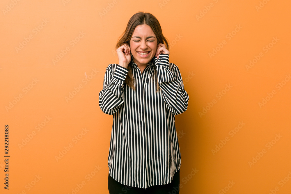 Young authentic charismatic real people woman against a wall covering ears with hands. Young authentic charismatic real people woman against a wall covering ears with hands.