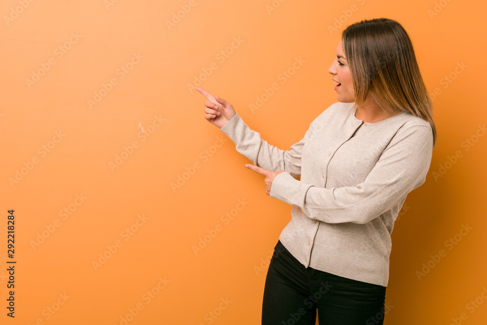 Young authentic charismatic real people woman against a wall excited pointing with forefingers away. Young authentic charismatic real people woman against a wall excited pointing with forefingers away.