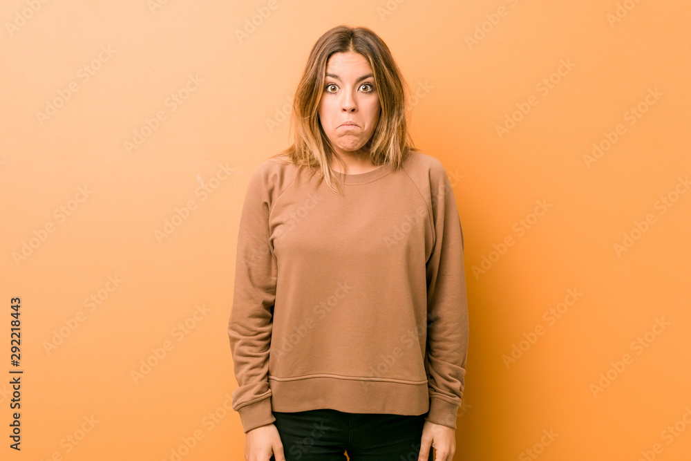 Obraz premium Young authentic charismatic real people woman against a wall shrugs shoulders and open eyes confused.