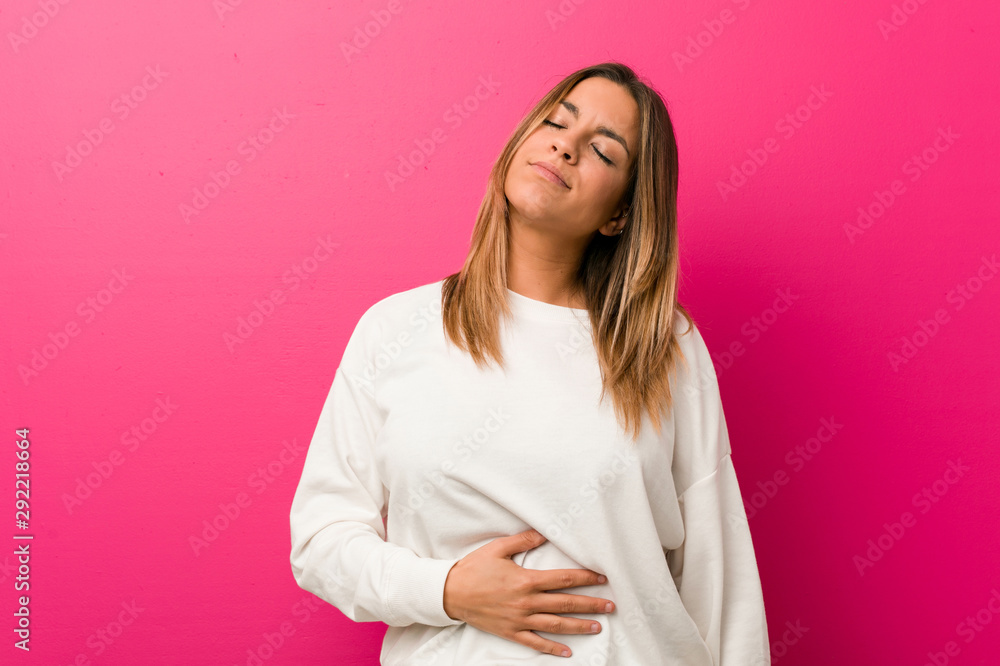 Obraz premium Young authentic charismatic real people woman against a wall touches tummy, smiles gently, eating and satisfaction concept.