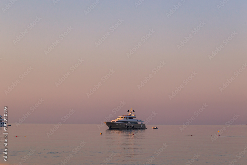 Luxury yacht on open sea at pink sunrise