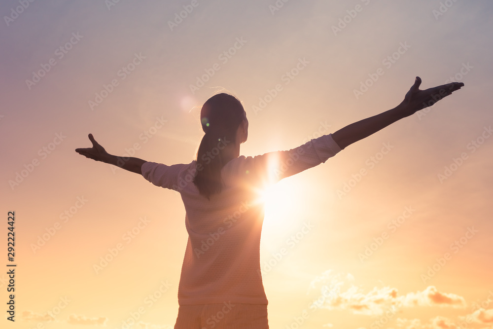 It's a new day concept. Happy woman in the sunshine lifting arms up to the sky.  - obrazy, fototapety, plakaty 