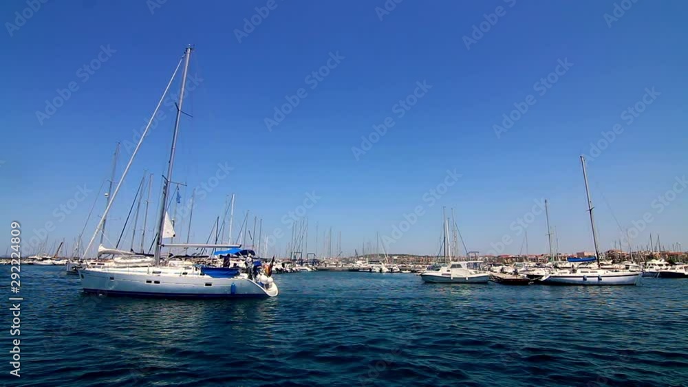 View from water sailing through a marina with anchored sail boats Sardinia Sardegna Italy View from water sailing through a marina with anchored sail boats Sardinia Sardegna Italy