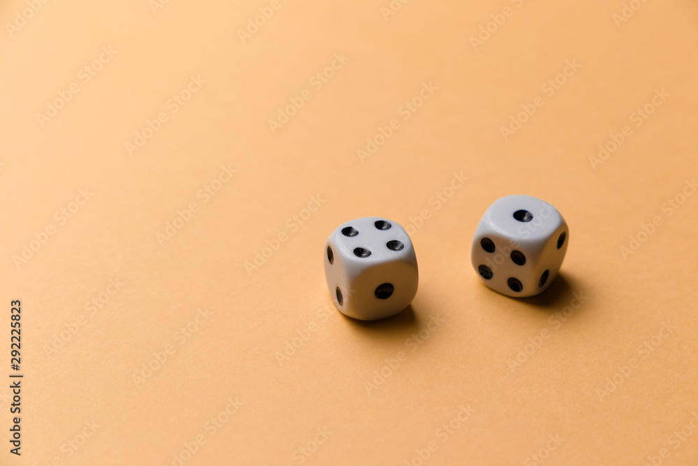 White gaming dice on orange background. Top view. Flat lay. Copy space. Game of chance concept. Close-up. Pastel colors White gaming dice on orange background. Top view. Flat lay. Copy space. Game of chance concept. Close-up. Pastel colors