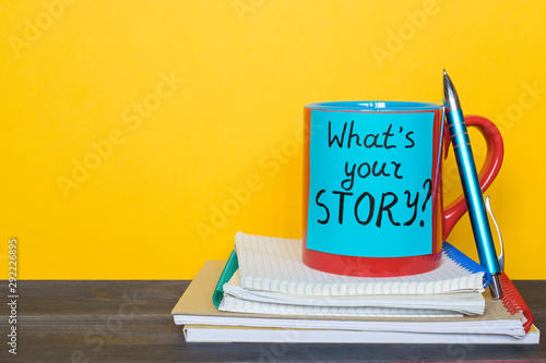 Red mug with words What`s your story on the yellow background.