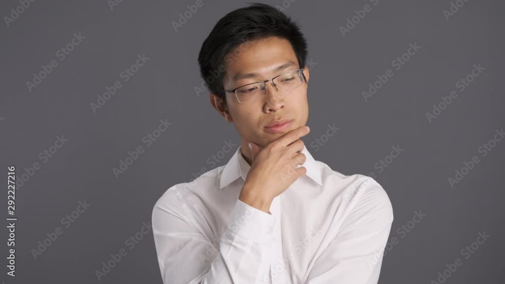 Young thoughtful asian man in eyeglasses thinking and nodding. Agree expression Young thoughtful asian man in eyeglasses thinking and nodding. Agree expression