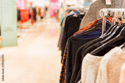 Sweaters hang on rails in modern clothes shop