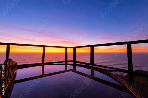 An amazing an idyllic view a wooden hot tub waiting us for some relaxation time during sunset and twilight before an awe night sky with a small crescent moon. A leisure activity at Chilean coastline