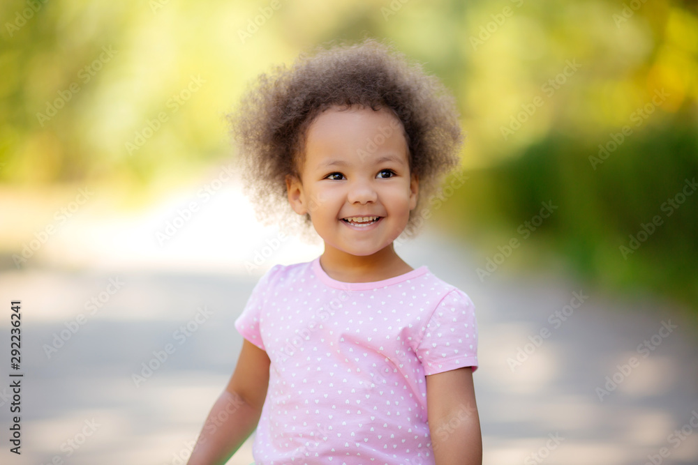 little African American girl in the summer on a walk smiling holding colorful candies little African American girl in the summer on a walk smiling holding colorful candies