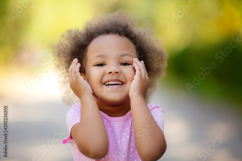 little African American girl in the summer on a walk smiling holding colorful candies