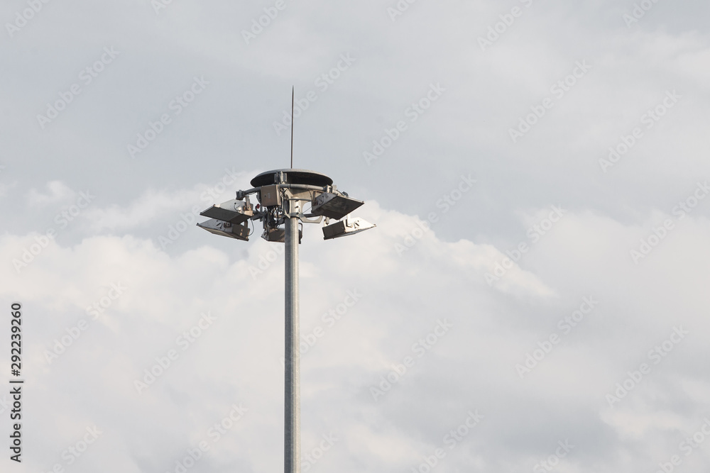 Lighting pole with halogen floodlight and  lightning conductor on the top of it. Metal construction with illuminator. Lighting coverage of a large area. City and urban illumination.