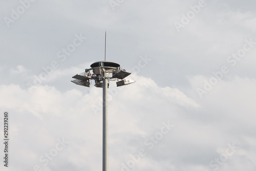 Lighting pole with halogen floodlight and lightning conductor on the top of it. Metal construction with illuminator. Lighting coverage of a large area. City and urban illumination.