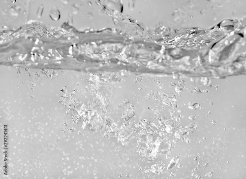 Water splashes as liquid is poured into the tank, abstract background