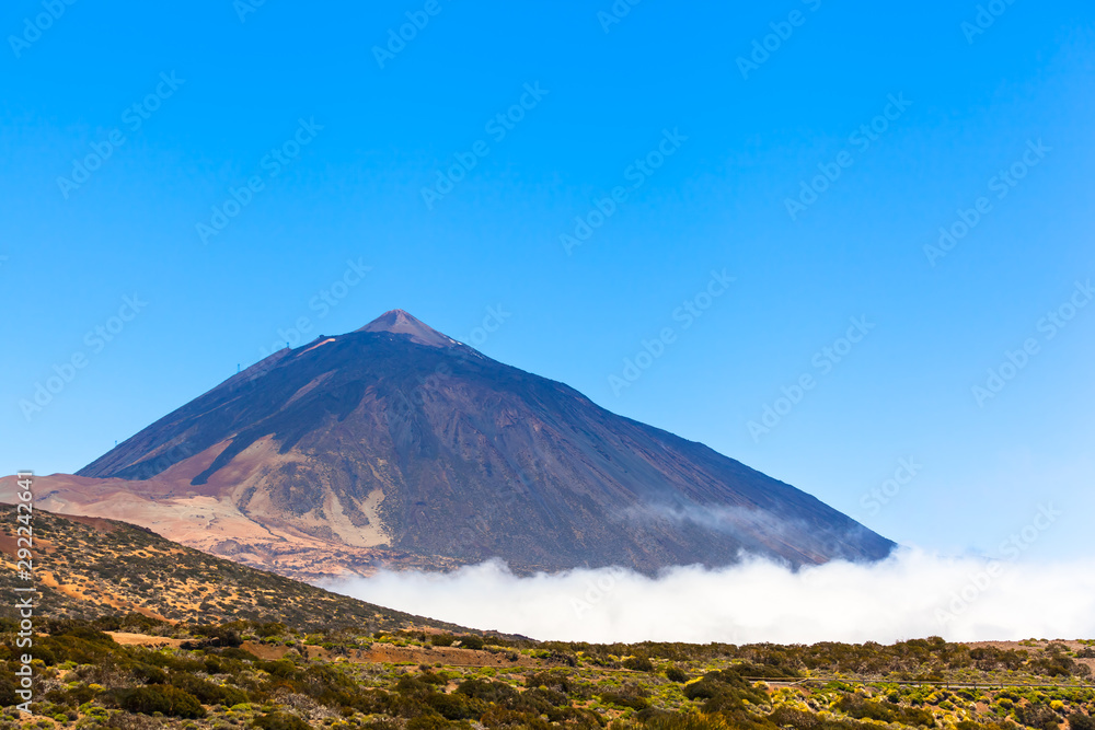 Tall Mountain Rock and Sky / View to Teide mountain above clouds at national park on Tenerife island, blue sky copy space