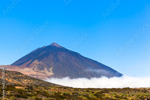 Tall Mountain Rock and Sky / View to Teide mountain above clouds at national park on Tenerife island, blue sky copy space