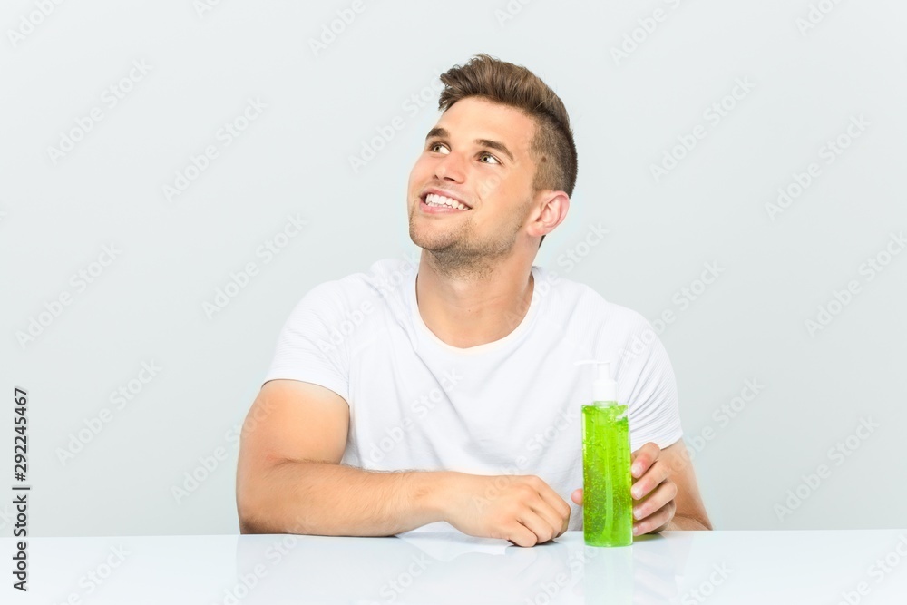 Young handsome man holding a aloe vera bottle smiling confident with crossed arms. Young handsome man holding a aloe vera bottle smiling confident with crossed arms.
