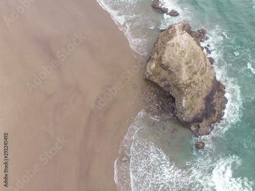 Beach landscape top view, sand, road and rock in the water. Sand, ocean texture with waves